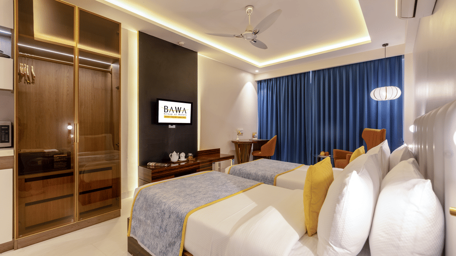 Premium bedroom with twin beds, blue drapes, and a glass-fronted wardrobe.