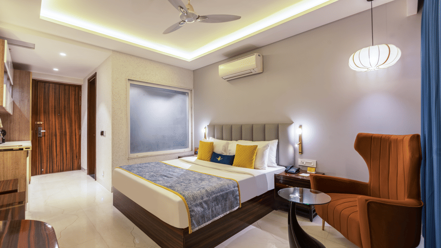 Spacious standard twin bedroom with blue curtains, modern headboards, and a glass-door wardrobe.