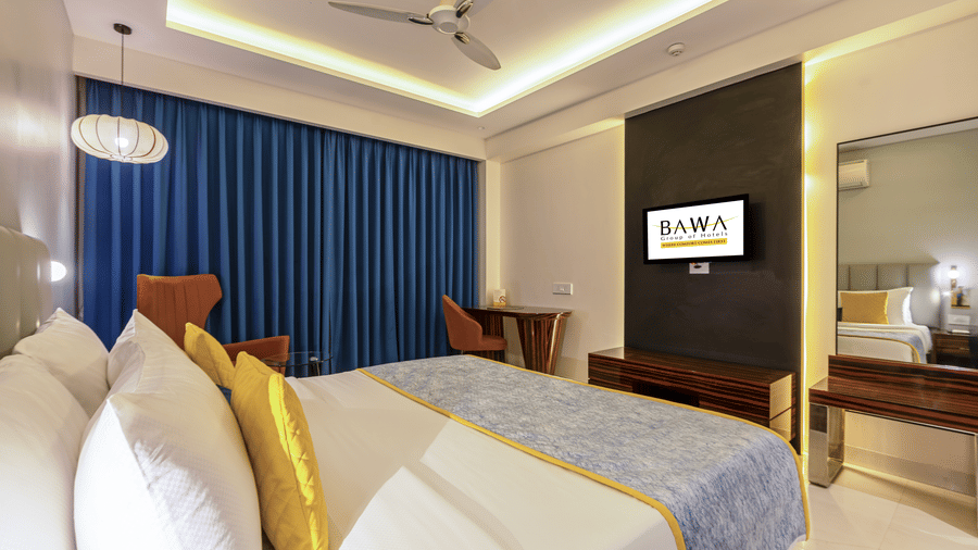 Standard king bedroom featuring a large wall-mounted TV, yellow accent pillows, and recessed ceiling lighting