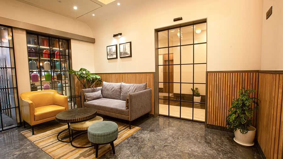 A corner view of the lobby at Hotel Bawa Regency, Dadar, featuring a comfy sofa and an interior plant to enhance the look and feel of the space.