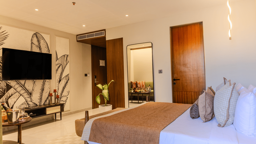Wide view of the bedroom entrance revealing a king size bed, television and botanical wall art at Hotel Bawa, Udaipur