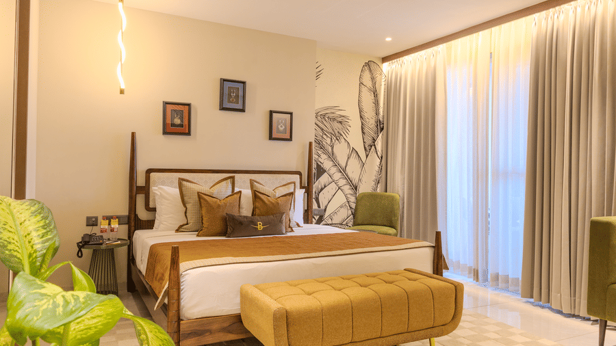 A king size bed with warm linen, large botanical mural in the Suite at Hotel Bawa, Udaipur