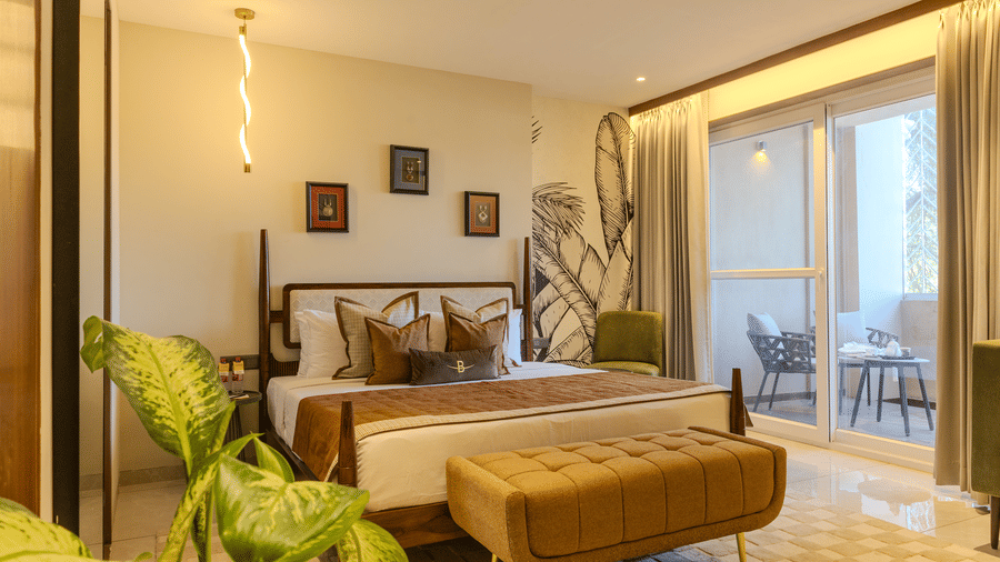 King size bedroom with a cushioned bench, sheer drapes and a sliding door opening to a private balcony at Hotel Bawa, Udaipur