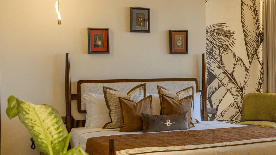 A Sunlit bedroom with a king size bed, decorative cushions and a detailed botanical wall mural in the Suite at Hotel Bawa, Udaipur
