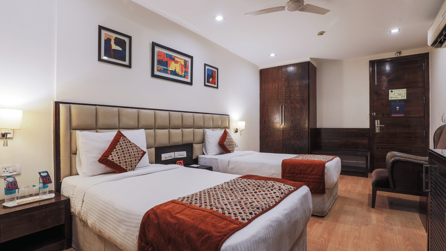 A large, well-appointed hotel room, with twin bed and a seating area with a sofa besides the door - Hotel Bluestone Prime (Nehru Place), New Delhi