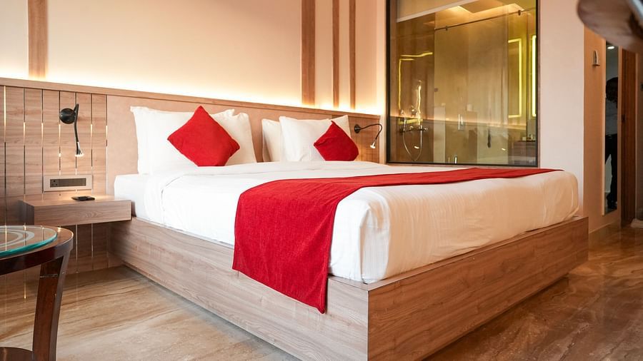 Well-appointed double room at Hotel City Inn, Varanasi, featuring modern interiors, wooden flooring, and a stylish glass-panelled bathroom.