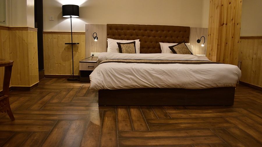Deluxe Room Apartment Type - lower angle view of a neatly tucked bed with wooden floor and interior and a bedside lamp next - Hotel Montana Vyoo