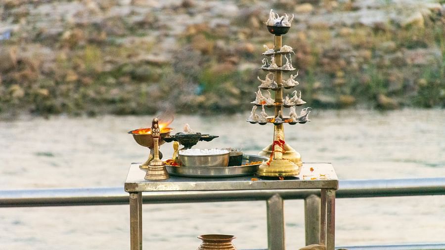 Hindu puja offering with lamps and flowers near a river.