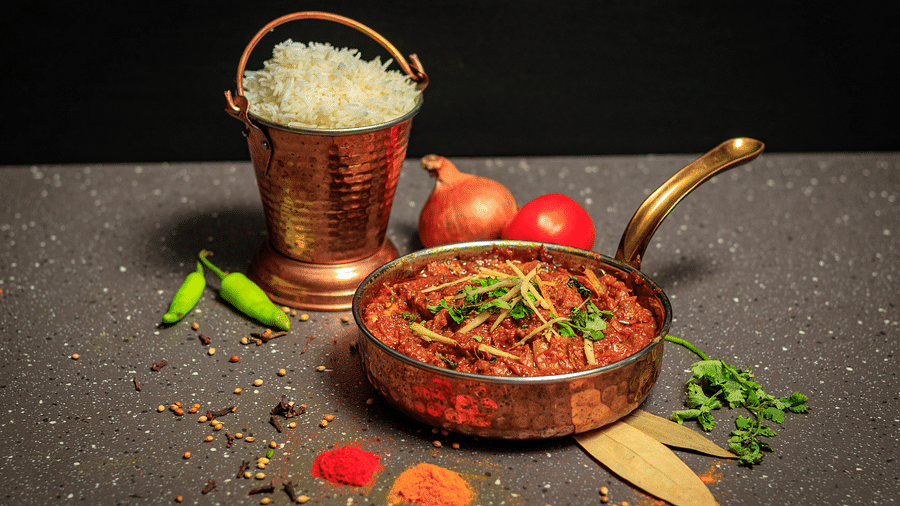 a curry and rice served on a table decorated with spices, bayleaves and chillies