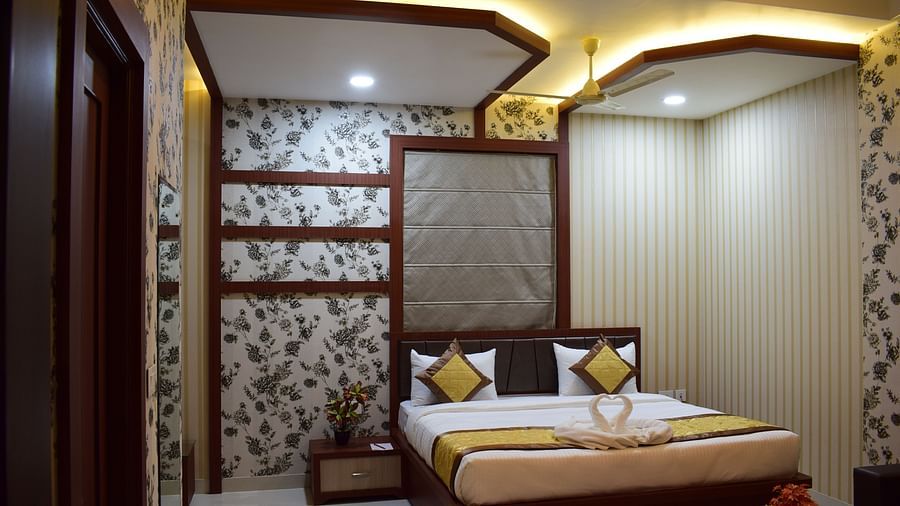 A spacious room featuring a large bed and a lit ceiling at Hotel Uday Palace.