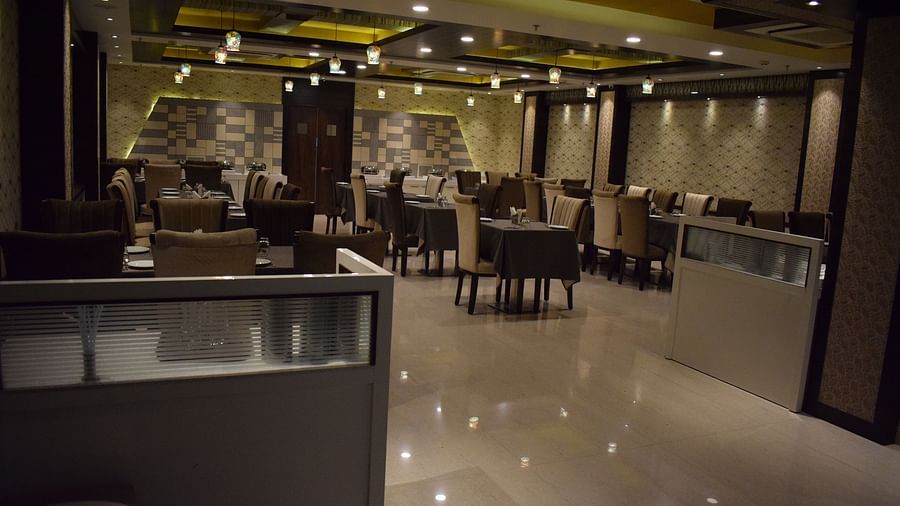 The dining area at Hotel Uday Palace showcases neatly arranged tables and chairs with dim, warm lighting.