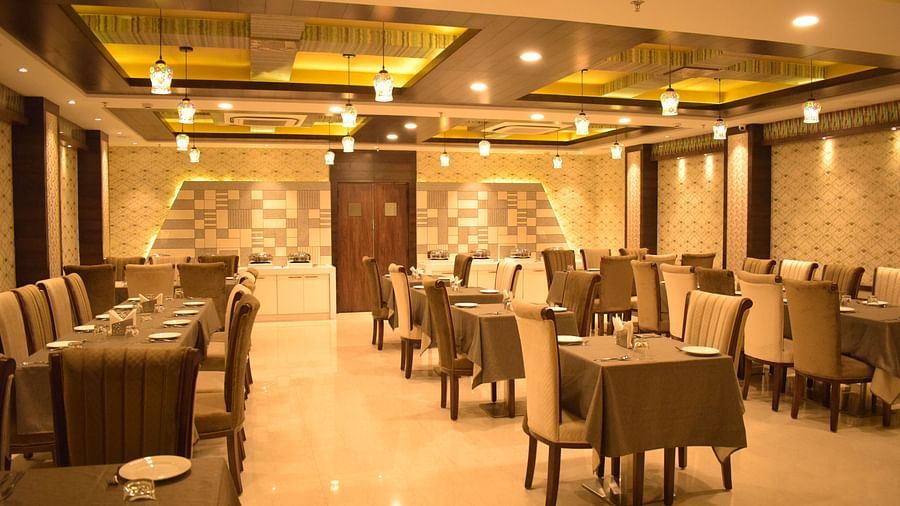The dining area at Hotel Uday Palace features neatly arranged tables and chairs with warm lighting.