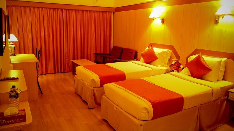  Hotel Yasodha Towers - Interior view of the bedroom featuring twin beds and wooden flooring in yellow ambient lighting