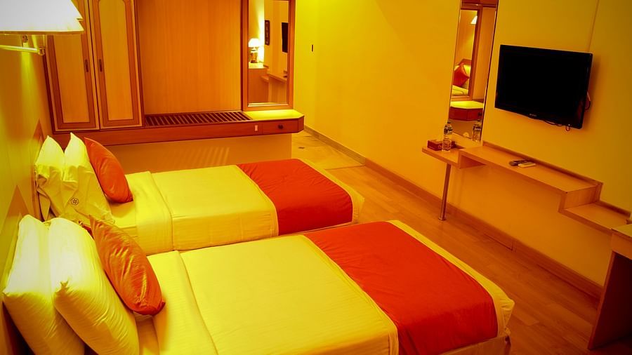  Hotel Yasodha Towers - Interior view of the bedroom featuring twin beds, wall mounted television and a wardrobe in yellow lighting