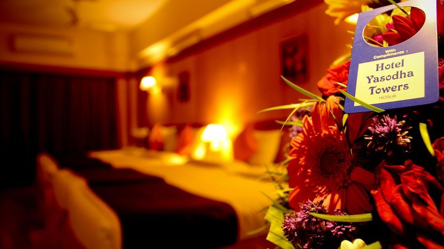  Hotel Yasodha Towers - Closeup shot of flowers and a door handle tag with double beds in the background