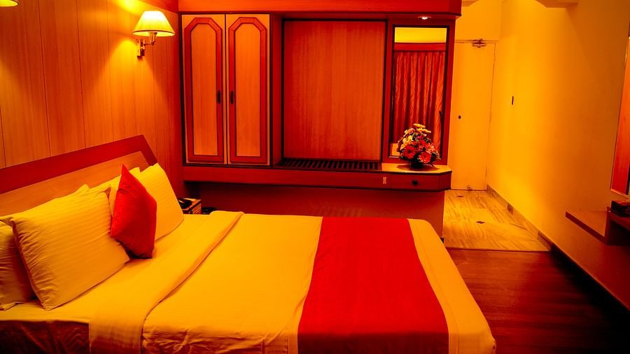  Hotel Yasodha Towers - Interior view of a bed room with wooden flooring featuring a queen size bed, a wardrobe and yellow ambient lighting