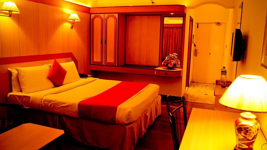 Hotel Yasodha Towers - Interior view of a bedroom a queen size bed, a wardrobe, and work desk with a yellow lamp