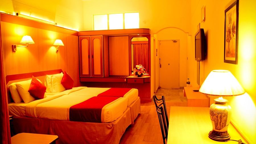 Hotel Yasodha Towers - Interior view of a bedroom a queen size bed, a wardrobe, and work desk with a yellow lamp