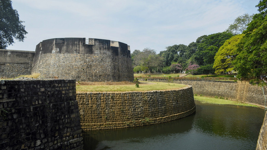 Palakkad Fort, one of the popular tourist places in Palakkad, beside calm water, surrounded by greenery under a bright sky, showcasing traditional architecture and peaceful surroundings