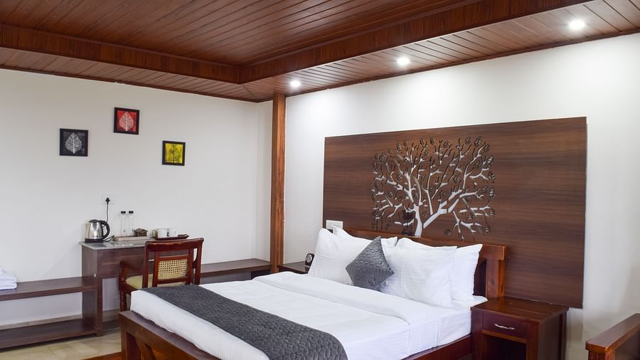 Image of the premium room at the resort featuring a king size bed with white mattress, pillow and a grey bed runner | Ibex Stays and Trails