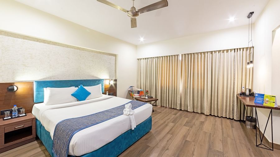 A spacious and well-lit hotel room at Icon Boutique Hotel by Bhagini, Domlur, with a comfortable bed, a work desk, and a seating area.