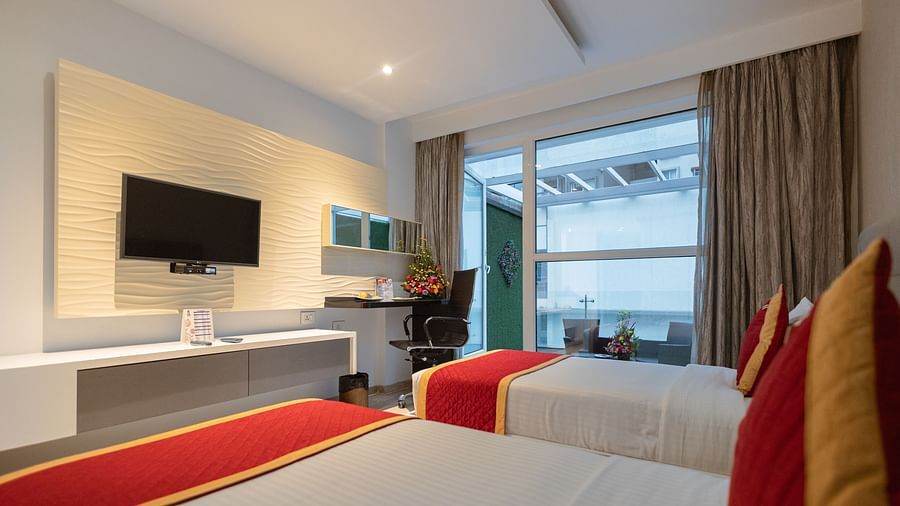 Two cozy beds and a wall-mounted TV in a Club twin room at Icon Premier Hotel by Bhagini, Devarabisanahalli
