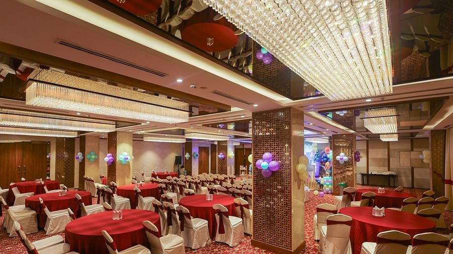 Blossom hall with stylish decor, lights, and round seating at Icon Premier Hotel by Bhagini, Devarabisanahalli