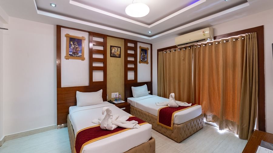 Comfort-focused twin bed setup with a muted golden curtain backdrop, warm lighting, and minimal clutter, providing a peaceful atmosphere for longer stays.