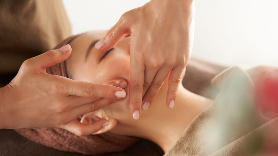 A woman getting a face massage by a masseuse