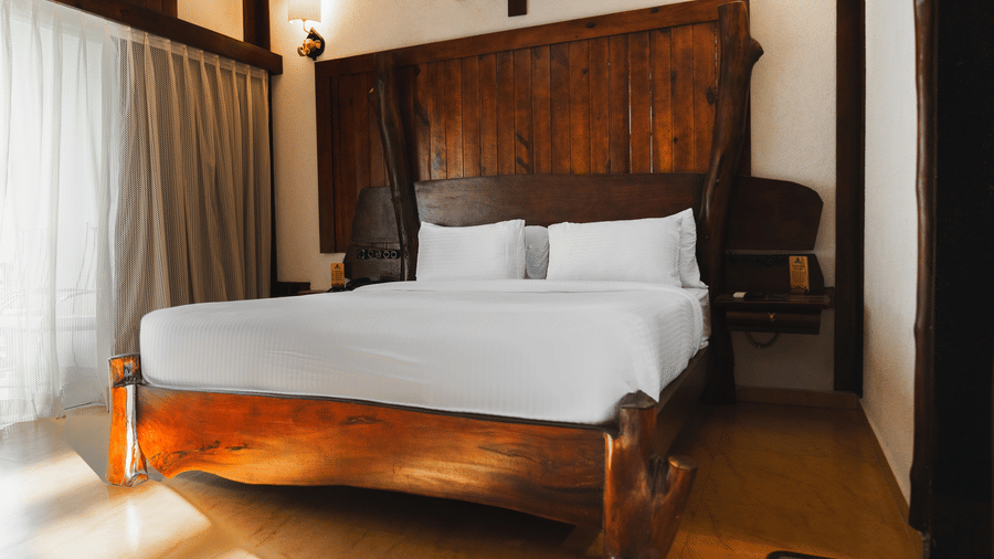 Luxury cottage room at Jagira Ananta Elite, Gir featuring a double size bed, bedside table, air-conditioner, window with curtains, etc.