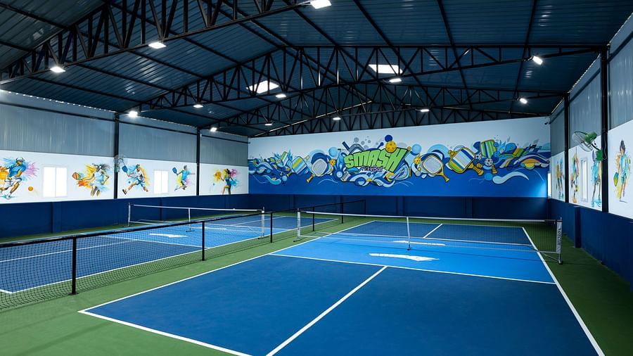 Indoor pickleball courts with blue and green surfaces and vibrant wall art, located at Jenneys Residency, Coimbatore.