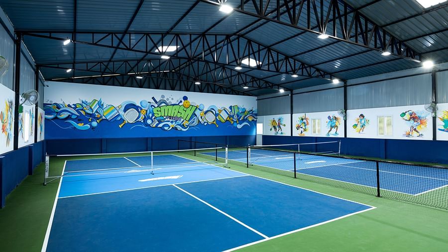 Indoor pickleball courts with blue and green flooring and colourful wall art, located at Jenneys Residency, Coimbatore.
