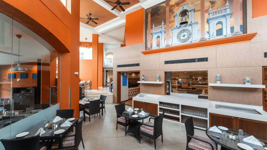 High-ceiling restaurant with a decorative mural wall and buffet area at Kenilworth Resort & Spa, Goa.