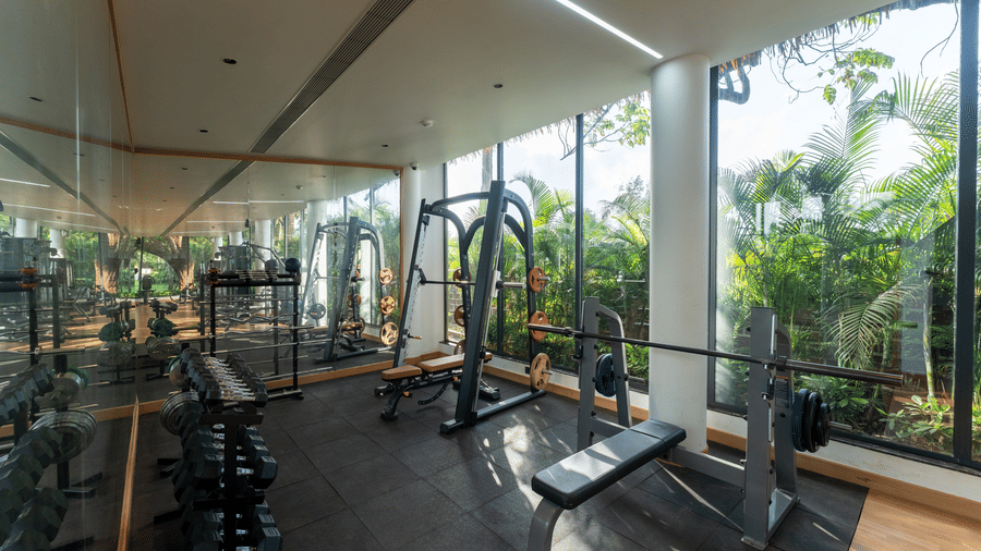 Bright gym room equipped with dumbbells and strength training benches at Kenilworth Resort & Spa, Goa.