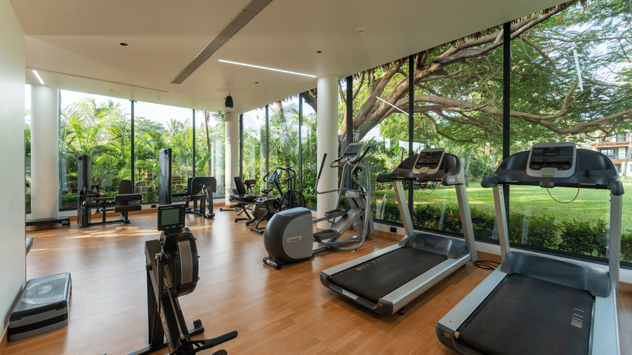 Modern fitness gym with treadmills and cardio equipment facing floor-to-ceiling glass windows at Kenilworth Resort & Spa, Goa.