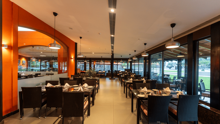 Spacious indoor restaurant dining hall with modern tables at Kenilworth Resort & Spa, Goa.