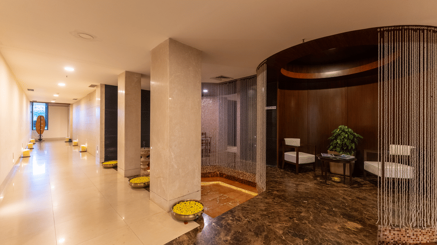 Spacious spa lobby corridor featuring warm ambient lighting and circular seating alcove at Kenilworth Resort & Spa, Goa.