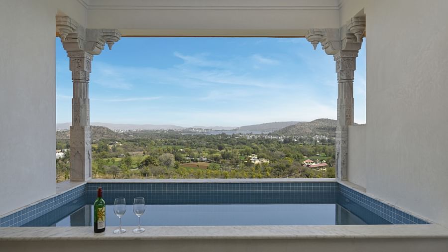 Overview of plunge pool overlooking a view at Khas Mahal by Fateh Collection, Udaipur featuring glasses kept on the side.