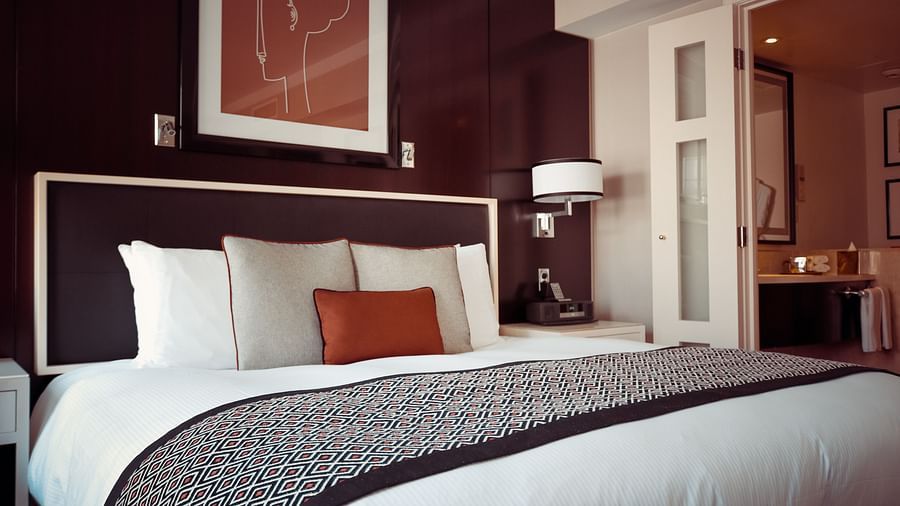 Side view of a double bed with grey bedsheet multiple pillows on a bed