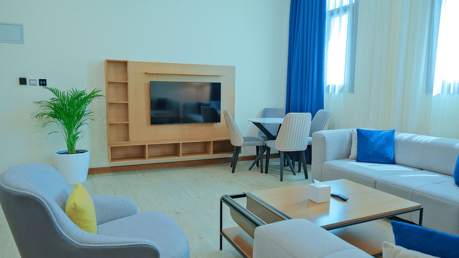 Living area at La Maison, Doha, with a couch, chairs, a coffee table, and a television on a stand.