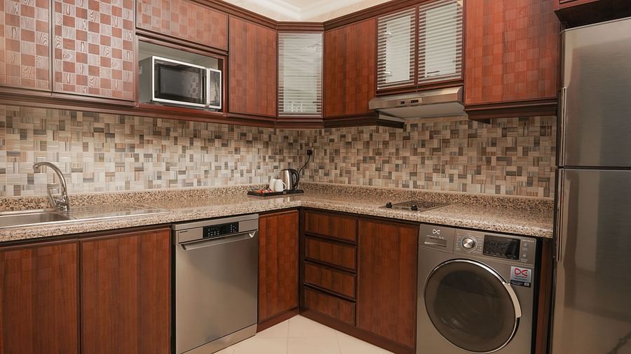 Overview of a kitchen with a washing machine and a fridge inside the Apartment - La Maison Hotel, Doha