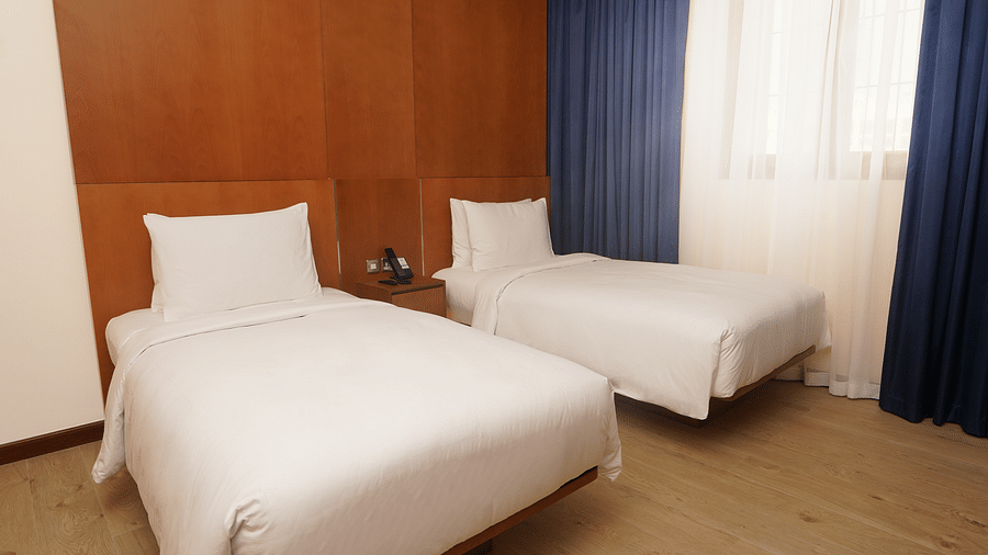 Twin beds with pillows on it inside one of the rooms - La Maison Hotel, Doha