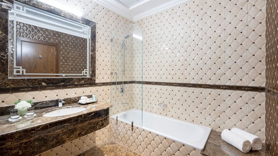 An elegant washroom with a bathtub and a sink in view - La Maison Hotel, Doha