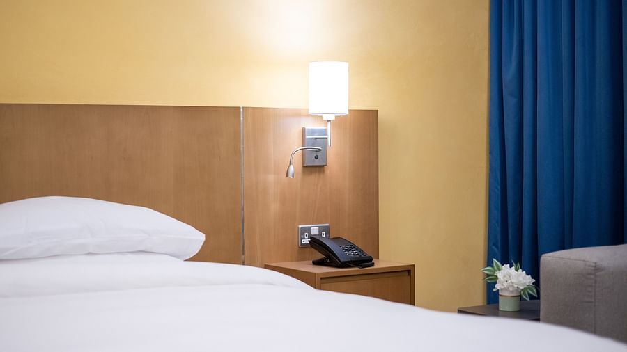 Large cushiony bed in a bedroom with a lamp above the telephone - La Maison Hotel, Doha