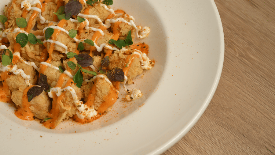 Creamy pasta topped with herbs and vegetables, elegantly plated at La Maison Hotel, Doha.