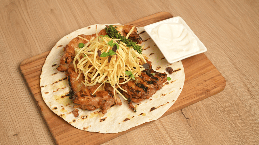 Grilled meat strips on flatbread topped with vegetables and sauce at La Maison Hotel, Doha.
