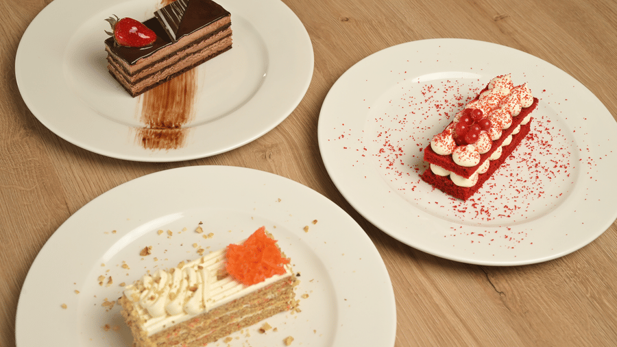 Selection of layered cakes and desserts served on white plates at La Maison Hotel, Doha.