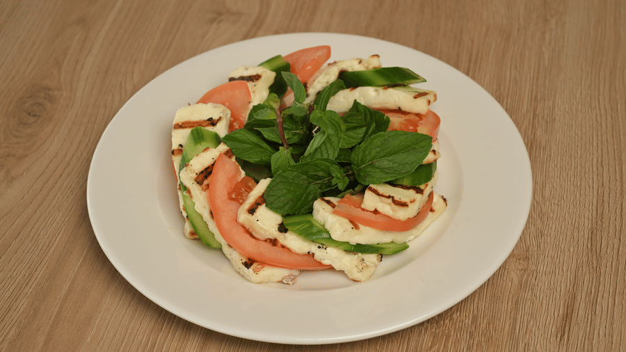 Fresh salad with sliced vegetables and leafy greens served on a white plate at La Maison Hotel, Doha.