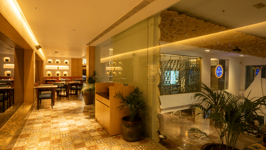 Corridor of The WIld Fork restaurant at La Marvella, Bengaluru which leads to a dining space filled with tables and chairs