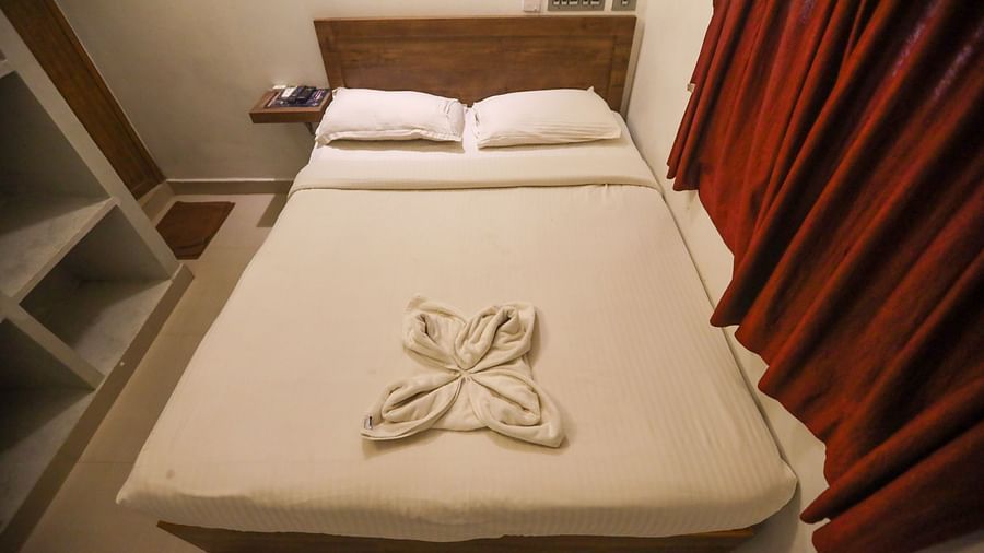 A top view of view of a double bed room with plushy bed and shelves and a wall painting hanging at La  Paradise Residency  
